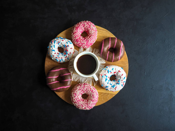 Una taza de café y dulces Donut en una mesa negra
. - Foto, imagen
