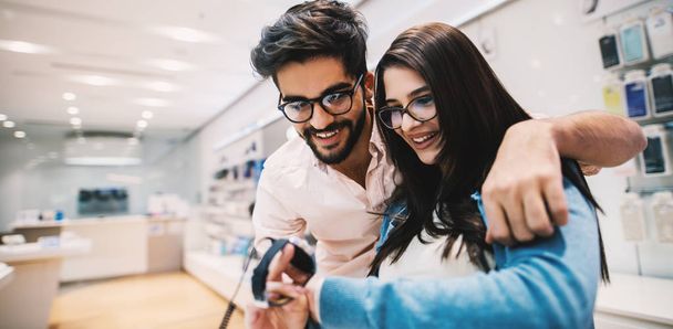 jeune couple heureux dans le magasin d'électronique en choisissant nouvelle smartwatch
 - Photo, image