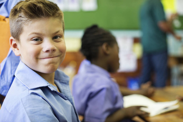 Valkoihoinen mies opiskelija hymyilee luokassa
 - Valokuva, kuva