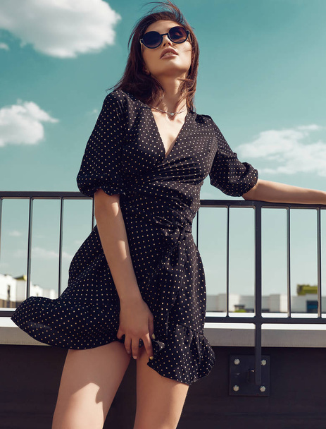 Portrait of a gorgeous bright brunette woman in fashion dress posing on the roof of a building - Photo, Image