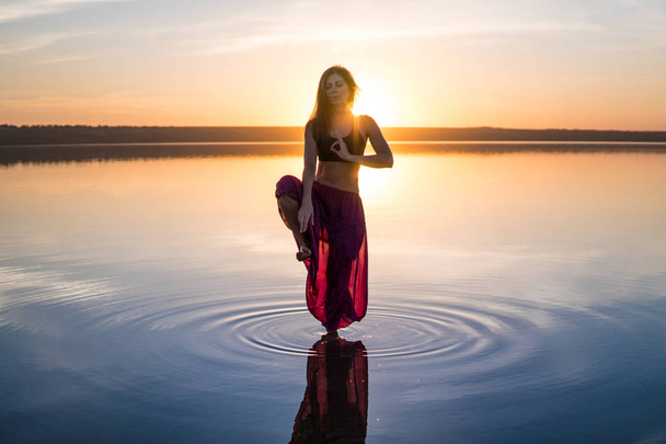 Silueta mujer yoga en la playa al atardecer
. - Foto, imagen