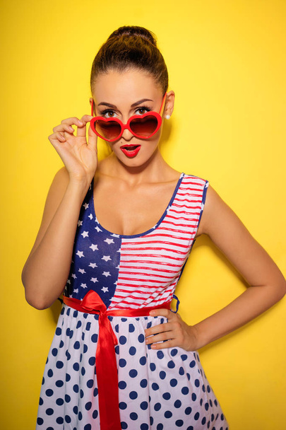 Colorful studio portrait of amazed young brunette woman with bright makeup holding heartshape sunglasses - Foto, immagini