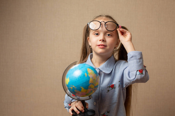 Petite fille dans des lunettes tenant globe
 - Photo, image