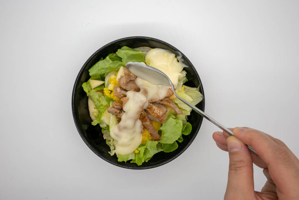 Χέρι κρέμα σε σάλτσα πάνω ψητό χοιρινό σπιτικό έκχυση σαλάτα με βιολογικά πράσινα λαχανικά που απομονώνονται σε λευκό φόντο. - Φωτογραφία, εικόνα