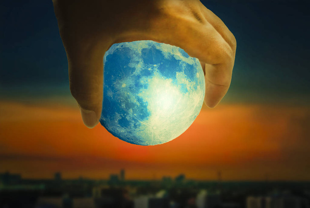 der Mond ist in einer Handvoll, der Hintergrund ist die Landschaft der Stadt des Abends. - Foto, Bild