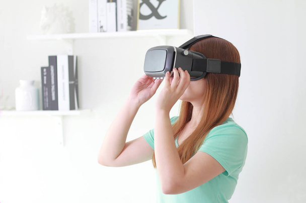 仮想現実の眼鏡を着て家で若い女性。仮想現実のヘッドセットは着用者の仮想現実を提供するヘッド マウント型デバイスです。. - 写真・画像