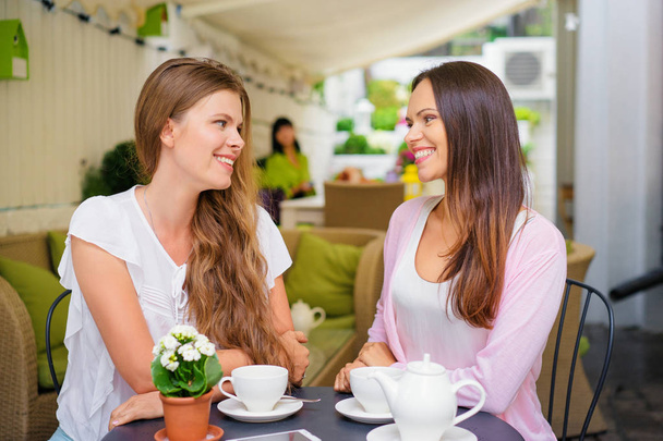 Two adult sisters talking while drinking tea at cafe. - Foto, Bild