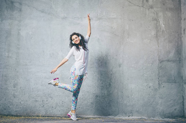  Happy young brunette woman with earphones is dancing outdoors. - Фото, зображення