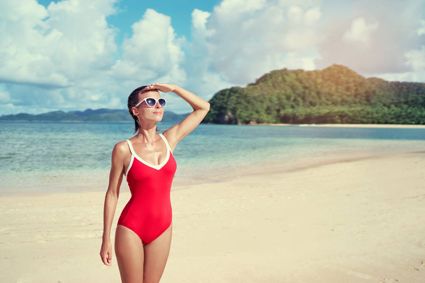 Outdoor portrait of pretty young woman in red swimsuit on beautiful tropical beach. - Foto, imagen