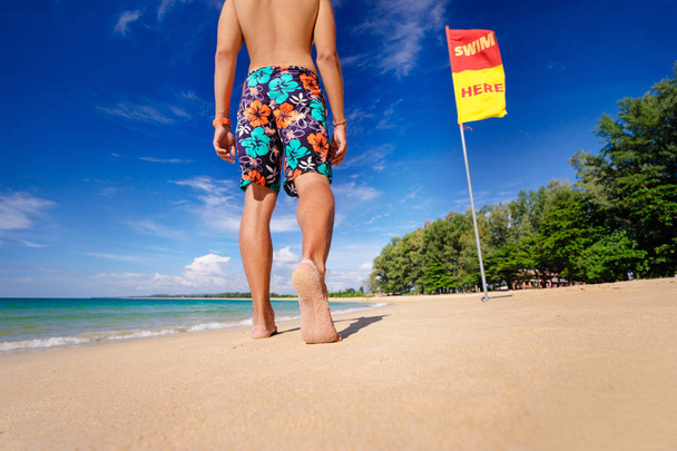 Barefoot man walking on beach at sunny day  - Foto, imagen