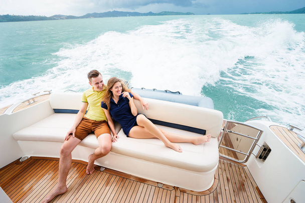 Romantic vacation and luxury travel. Young loving couple sitting on the sofa on the modern yacht deck - Photo, Image