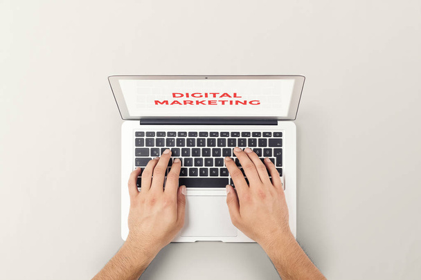 Man typing digital marketing on laptop keyboard top view stock photograph - Photo, Image