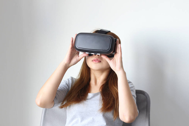 Jeune femme portant des lunettes de réalité virtuelle à la maison. Un casque de réalité virtuelle est un dispositif monté sur la tête qui fournit la réalité virtuelle pour le porteur
. - Photo, image