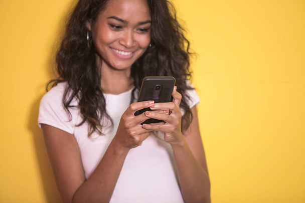 красивая азиатская женщина улыбается, когда пишет смс на мобильный
 - Фото, изображение