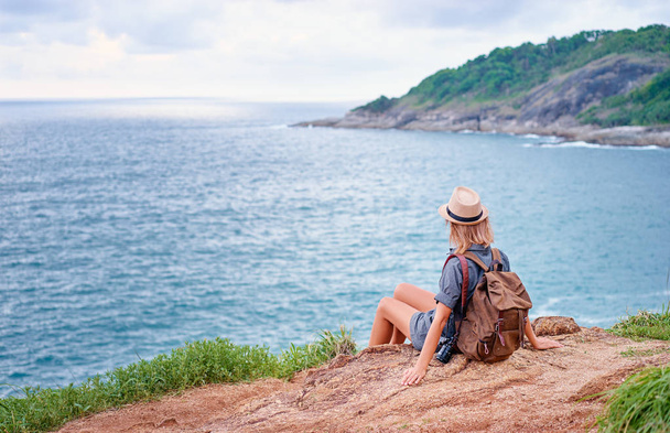 Young traveling woman with camera and rucksack enjoying sea view. - Foto, imagen