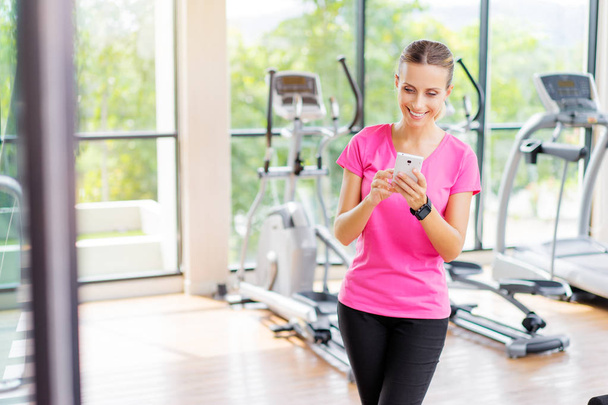 Attractive young woman using smartphone in gym. - Fotó, kép