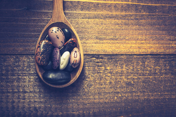 Pilha de feijões coloridos em fundo de madeira escura
 - Foto, Imagem