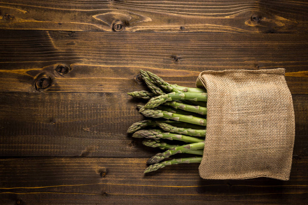 Fresh Asparagus in Juta Bag on Wooden Background - Photo, Image