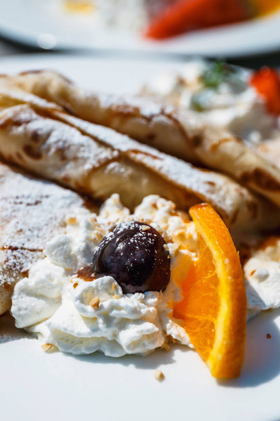 pancake with apple filling decorated with whipped cream, oranges and cherry - Photo, Image