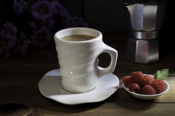 Taza de café con tazón de frambuesas, cafetera italiana y flores en la mesa de madera
 - Foto, Imagen