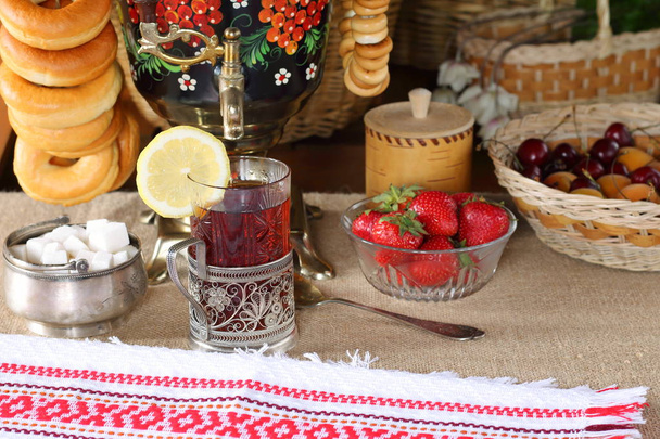 Стакан черного чая, самоваров и летних ягод и фруктов
. - Фото, изображение
