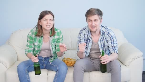 若いカップルが自宅のテレビでスポーツを見て - 映像、動画
