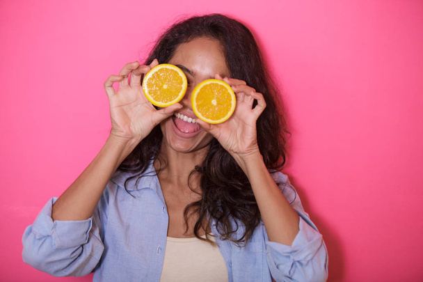 close up portrait of expressive face of asian woman play woth slices of lemon on pink background - Zdjęcie, obraz