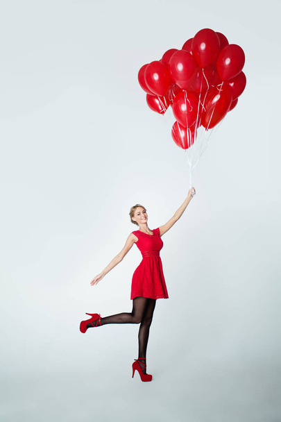 Mulher alegre em vestido vermelho com balões, fundo de férias
 - Foto, Imagem
