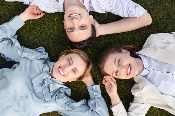 Three smiling happy employers lying on the grass - Photo, image