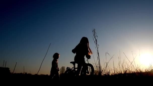 Silhouette of two little girls who play with bicycle - Footage, Video