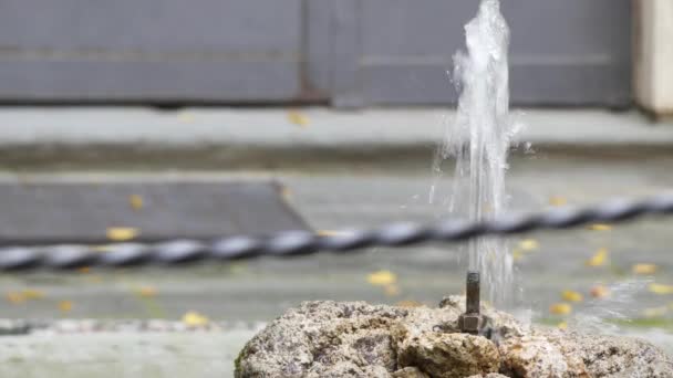Malé kovové fontána bije z kamene v městském parku letní. - Záběry, video