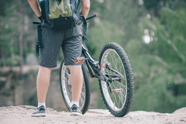 cropped image of male cyclist with backpack standing near bicycle  - 写真・画像