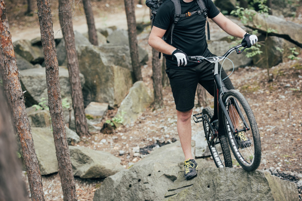 levágott kép férfi extreme kerékpáros bukósisakot állandó, hegyi kerékpár-kő-erdő - Fotó, kép