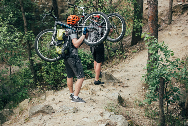sisakok szállító mountain bike-erdő-férfi extrém kerékpárosok  - Fotó, kép