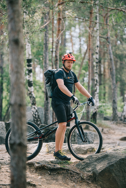 fiatal férfi extreme kerékpáros állandó bukósisakot, hegyi kerékpár, erdő - Fotó, kép