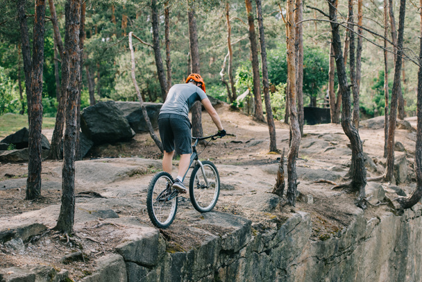 vista trasera del ciclista masculino en casco realizando acrobacias en bicicleta de montaña
  - Foto, imagen