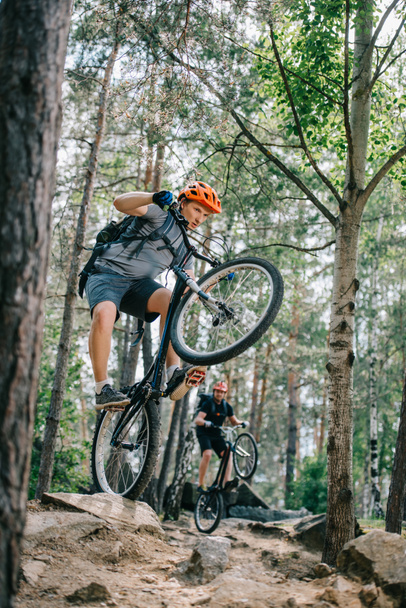 nuori kokeiluversio moottoripyöräilijät ratsastus takapyörillä kauniissa metsässä
 - Valokuva, kuva