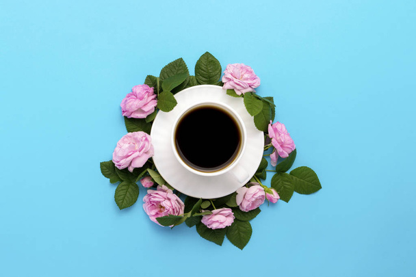 White cup with black coffee and pink roses lined around on a blue background. Flat lay, top view. - Photo, Image