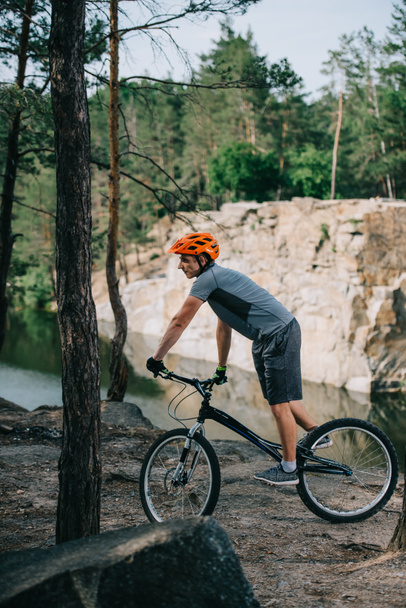 joven ciclista de trial montar al aire libre frente al lago en el bosque
 - Foto, imagen