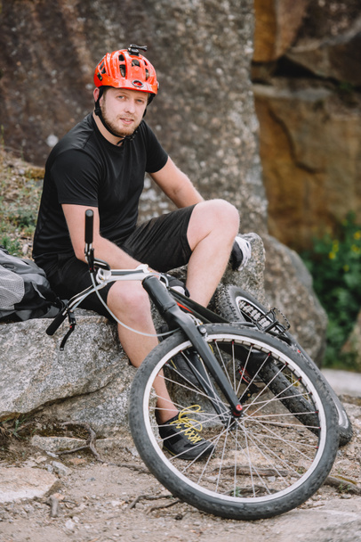 komea nuori kokeiluversio biker rentouttava kiviä polkupyörän ulkona ja katsot kameraa
 - Valokuva, kuva