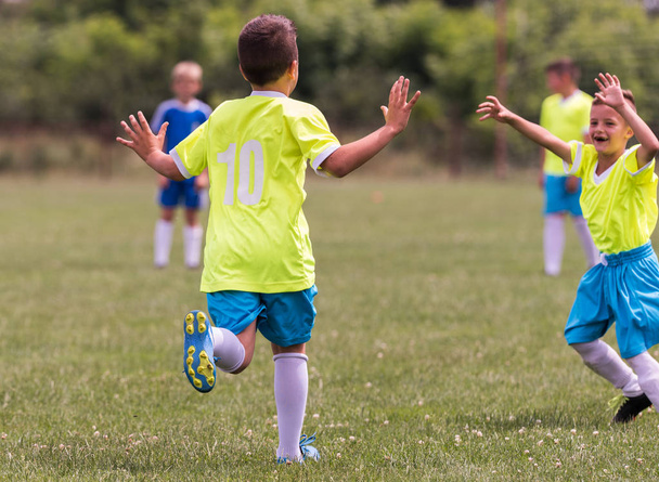 Детский футбол - маленькие дети игроки празднуют в объятиях после победы
 - Фото, изображение