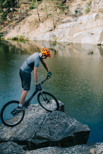 urheilullinen kokeiluversio biker tasapainottaminen kivinen kalliolla järven yli
 - Valokuva, kuva