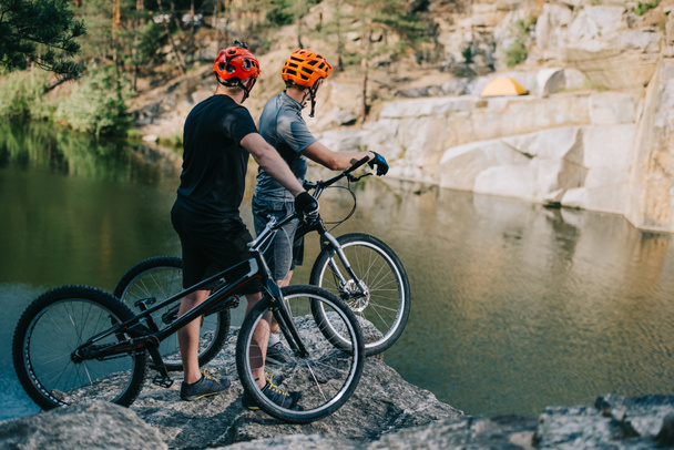 aşırı deneme bisikletçileri dağ Gölü önünde kayalık uçurum tutuyoruz - Fotoğraf, Görsel