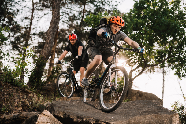 sportos fiatal próba motorosok lovaglás a sziklák, a fenyves erdő - Fotó, kép