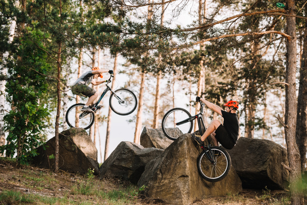 ciclistas de trial activos realizando acrobacias en rocas al aire libre
 - Foto, Imagen