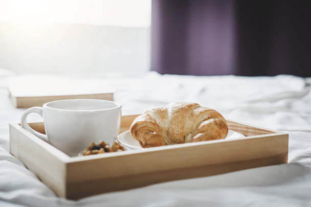Morning cup of coffee and Croissant on the bed with old book. - Foto, immagini