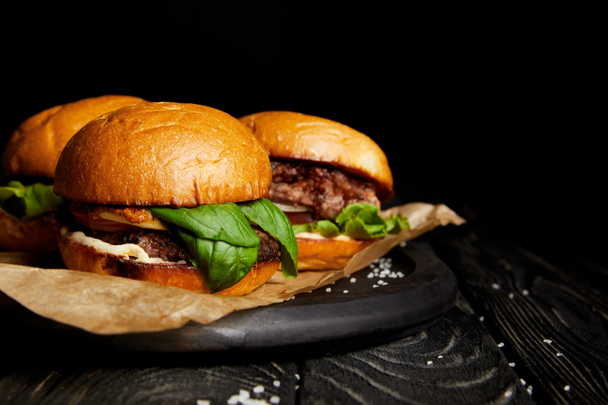 Junkfood mit heißen leckeren Burgern auf Holzbrett - Foto, Bild