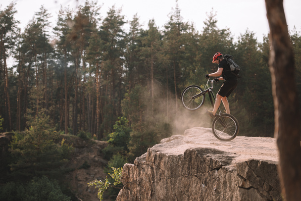 trial biker balancing on back wheel on rocks outdoors - 写真・画像