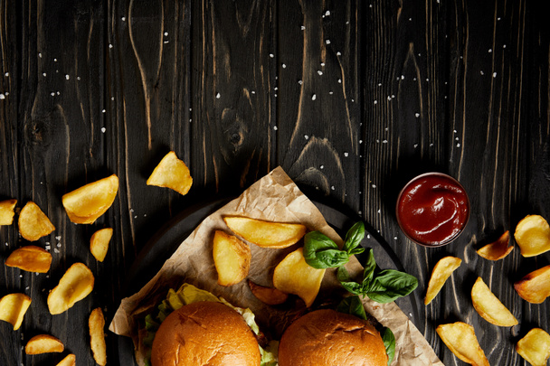 Top view of tempting hamburgers and fried potatoes on wooden table - Photo, Image