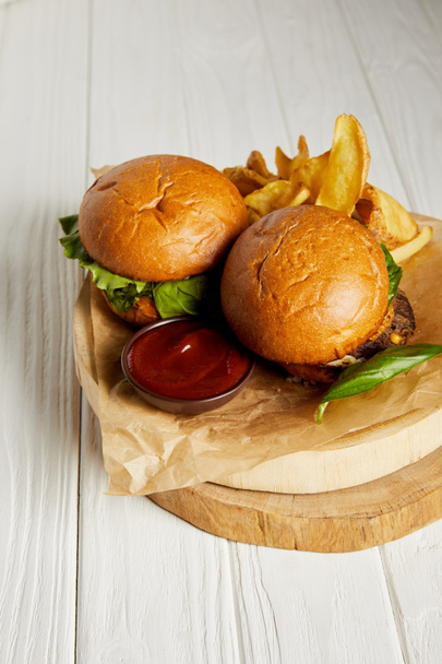 Hamburgers et frites au ketchup servis sur papier artisanal sur table blanche
 - Photo, image